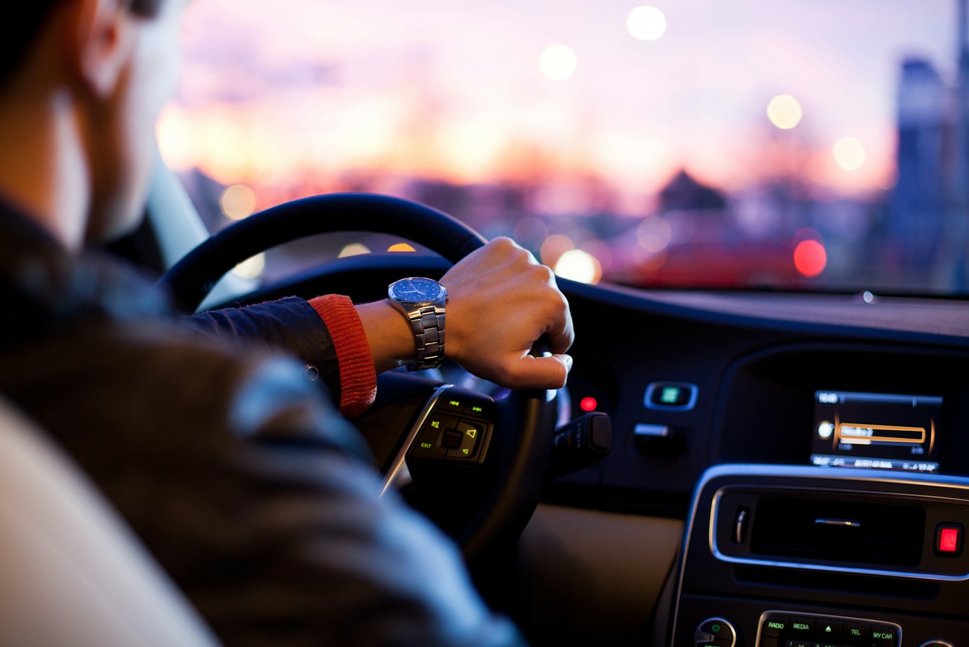 Driver's hand on the steering wheel with the road ahead